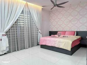 a bedroom with a pink bed and a ceiling fan at Royal Palace Homestay in Taiping