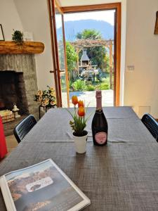 a bottle of wine and a vase with flowers on a table at Ca' Sunin Bellagio - mountains view apartment in Bellagio