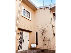 a building with a white door and a tree at Tuktuk House in Kawagoe