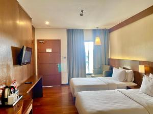 a hotel room with two beds and a television at Oak Tree Emerald Semarang in Semarang