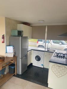 a kitchen with a refrigerator and a washing machine at Delightful chalet, overlooking estuary! in Ferryside