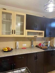 una cocina con armarios de madera y una bandeja de fruta en la barra en Dighomi Apartment, en Tiflis