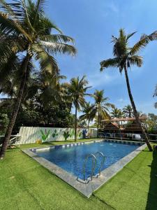 una piscina con palmeras en el fondo en Kranti Yoga Tradition - Beach Resort, en Patnem