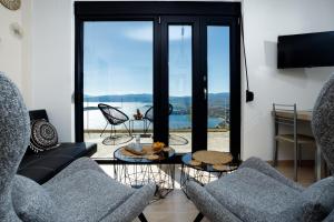 uma sala de estar com duas cadeiras e uma porta de vidro em Endless View Apartment em Elliniká