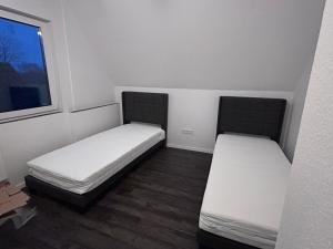 two beds in a small room with a window at Ferienwohnung Landliebe in Ihlow