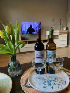two bottles of wine and glasses on a table at Apartament Asspazja in Stronie Śląskie