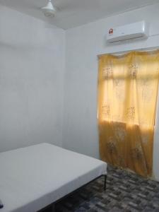 a room with a bed and a yellow curtain at Homestay Idaman B B with 2 room aircond 2 Quen Bed and Not Sharing Room -Privacy in Kuala Terengganu