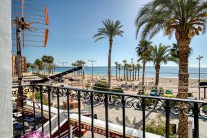 uma varanda com vista para a praia e palmeiras em El Desembarco em Villajoyosa