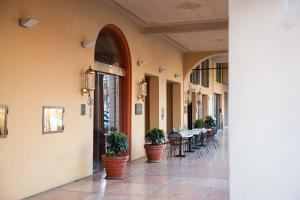 un corridoio con piante in vaso, tavoli e sedie di Phi Hotel Dei Medaglioni a Correggio