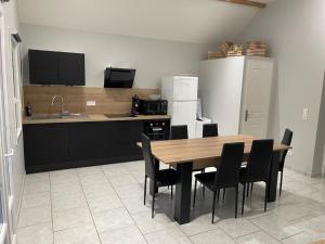 a kitchen with a wooden table and black chairs at Chalet et étangs 2 chambres in Henrichemont