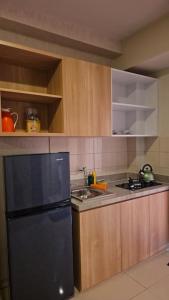 La cuisine est équipée d'un réfrigérateur noir et de placards en bois. dans l'établissement 2 BR The Oak Tower Apartment 9th Floor, à Jakarta