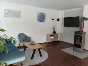ein Wohnzimmer mit einem Sofa, einem Tisch und einem TV in der Unterkunft Ferienhaus Oberhof in Weissenbach am Lech