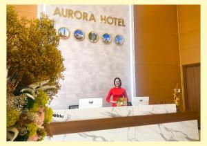 een vrouw die achter een toonbank staat met twee laptops bij Aurora Hotel Măng Đen in Kon Von Kla