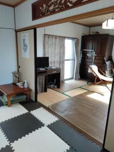 Habitación con sala de estar con mesa y escritorio. en ゲストハウスジェイズ en Amagi