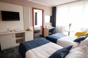 a hotel room with two beds and a television at Airport Hotel Budapest in Vecsés