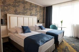 a hotel room with two beds with blue pillows at Airport Hotel Budapest in Vecsés