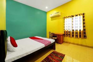 a bedroom with a bed and a window and a table at OYO Flagship Raj Munmun Hotel in Dhanbād