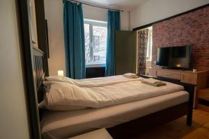 - une chambre avec un lit, une télévision et un mur en briques dans l'établissement 2BDR Flat in Centre Sofia (NDK), à Sofia
