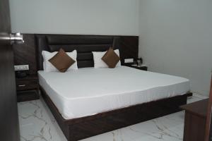 a bed with white sheets and pillows in a room at HOTEL PR VILLA in Gandhinagar