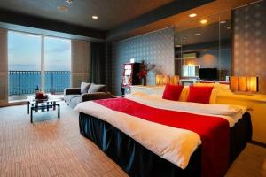 a large bedroom with a large bed and a living room at HOTEL CALM Leisure Hotel in Beppu