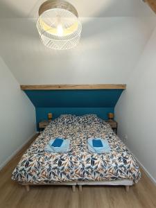a bedroom with a bed with a blue headboard and a light at Duplex F2 au pied des pistes du lac blanc in Orbey