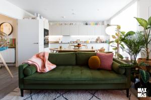 un sofá verde en una sala de estar con cocina en Charming 2-Bed with private balcony & free parking, en Dagenham