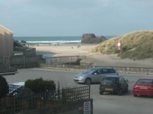 two cars parked in a parking lot next to a beach at Surf's Up in Perranporth, Cornwall Coastal Holidays in Perranporth