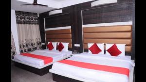 2 letti in una camera da letto con cuscini rossi e bianchi di Hotel Lords Paradise , Katra a Katra