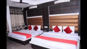 two beds in a bedroom with red and white pillows at Hotel Lords Paradise , Katra in Katra