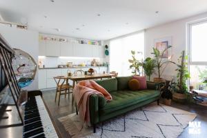 sala de estar con sofá verde y cocina en Charming 2-Bed with private balcony & free parking, en Dagenham