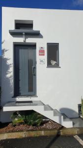 een wit gebouw met een zwarte deur en een raam bij Caminhos nos Levam pela Ilha in Ponta Delgada