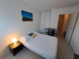 - une chambre avec un lit et une table avec une lampe dans l'établissement Résidence Les Académies Aixoise, à Aix-en-Provence