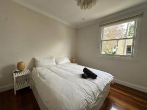 ein Schlafzimmer mit einem weißen Bett mit einem schwarzen Hut darauf in der Unterkunft 3 Bedroom House Family Friendly Surry Hills 2 E-Bikes Included in Sydney