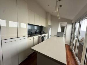 cocina con armarios blancos y encimera blanca en 3 Bedroom House Family Friendly Surry Hills 2 E-Bikes Included, en Sídney