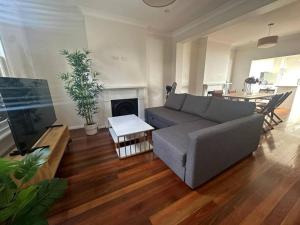 ein Wohnzimmer mit einem Sofa und einem Tisch in der Unterkunft 3 Bedroom House Family Friendly Surry Hills 2 E-Bikes Included in Sydney