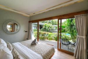 a bedroom with a bed and a sliding glass door at The Elementum in Uluwatu