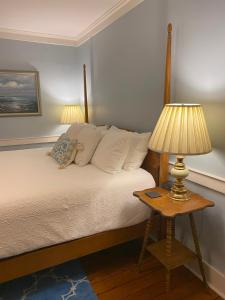 a bedroom with a bed with a table with a lamp at Spouter Inn Bed & Breakfast in Lincolnville