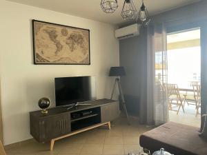 uma sala de estar com uma televisão de ecrã plano e um sofá em Bel Appartement en plein cœur de Folelli em Penta-di-Casinca