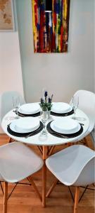 a white table with plates and wine glasses on it at Modern & Stylish - Art Atelier Apartment in Skopje