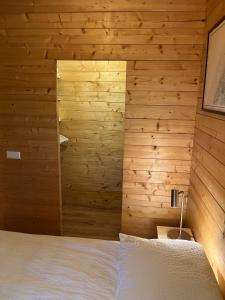 a bedroom with wooden walls and a white bed at Luxe en ruim chalet met airco bij Leekstermeer in Matsloot