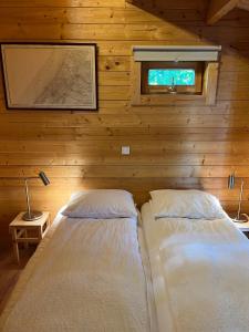 two beds in a room with wooden walls and a window at Luxe en ruim chalet met airco bij Leekstermeer in Matsloot
