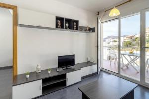 ein Wohnzimmer mit einem TV und einem großen Fenster in der Unterkunft Cau del Llop 691 Apto con piscina comunitario in Llança