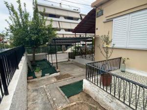 un pequeño patio con una valla y un edificio en Lovely House with Private Carport & Shady Veranda, en Atenas