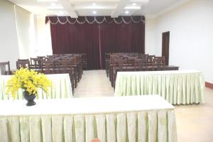 una sala de conferencias con mesas y sillas con flores amarillas. en Coecco Xieng Khouang Hotel en Ban Nafèng