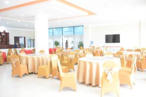 Salón de banquetes con mesas y sillas y TV de pantalla plana en Coecco Xieng Khouang Hotel, en Ban Nafèng