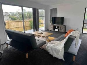 a living room with a couch and a table and a tv at Cozy 3BR West Auckland in Auckland