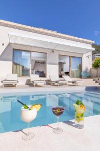 a villa with a swimming pool with two cocktails at Brand New Villa Carmelita Exclusive with free Smart Car in Dubrovnik