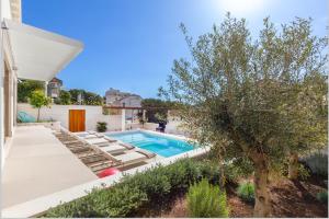 a swimming pool with lounge chairs and a tree at Brand New Villa Carmelita Exclusive with free Smart Car in Dubrovnik