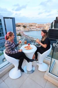 Duas mulheres sentadas numa mesa numa varanda a comer comida. em Holiday Inn Express - Malta, an IHG Hotel em St Julian's