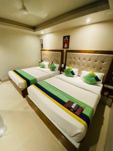 two beds in a hotel room with green pillows at New Hotel Amber International Near International Airport T2 in Mumbai
